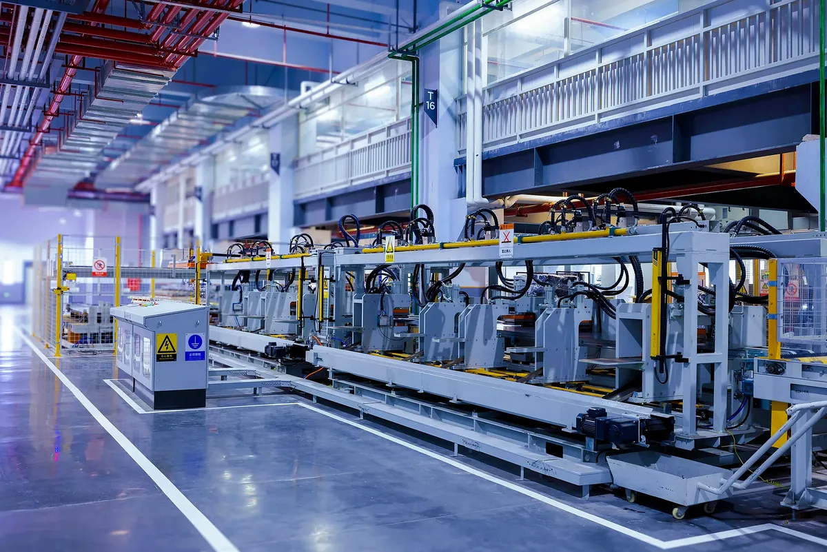 Automated factory equipment with conveyor frames and yellow safety fencing.